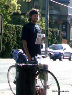 Picture of homeless person selling newspapers with a bike