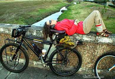 Picture of woman laying down next to bike for bikepacking 